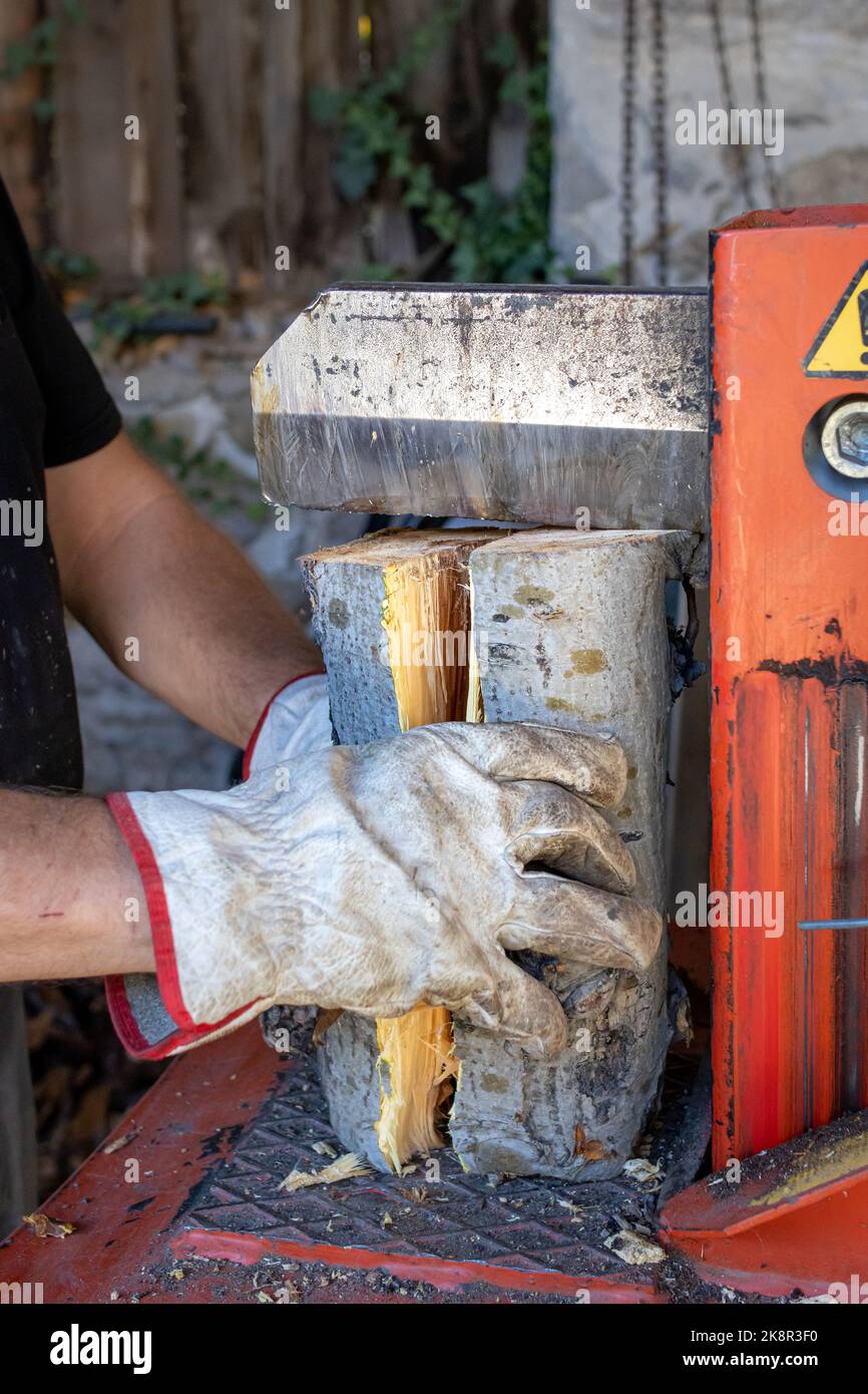 Man splitting wood with hydraulic log splitter machine Stock Photo - Alamy