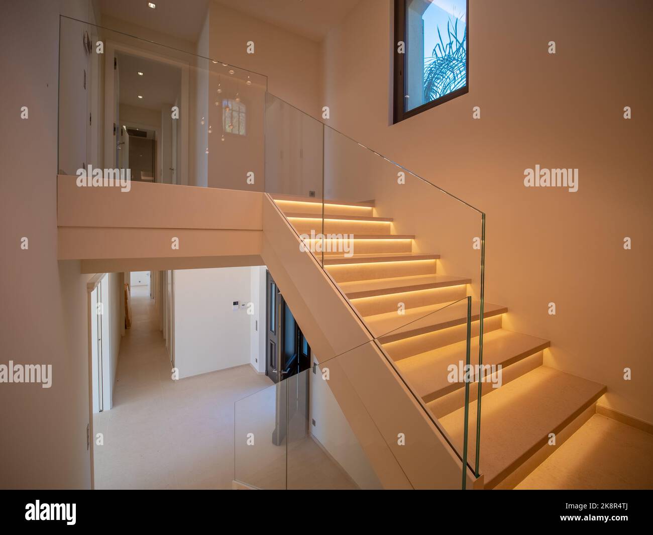 A modern staircase with led lights in marble and glass stairwell of a villa in a beige interior Stock Photo