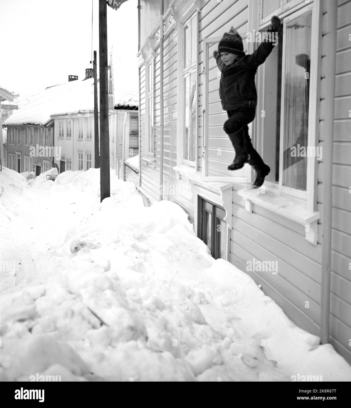 Mandal 19660115. Mandal was buried by large snow masses during the New Year weekend. A new large snowfall will mean disaster. Here Johnny jumps out through a window in Nordgaten. The door is on the nearest snowed down. Photo: Aage Storløkken Current / NTB Stock Photo