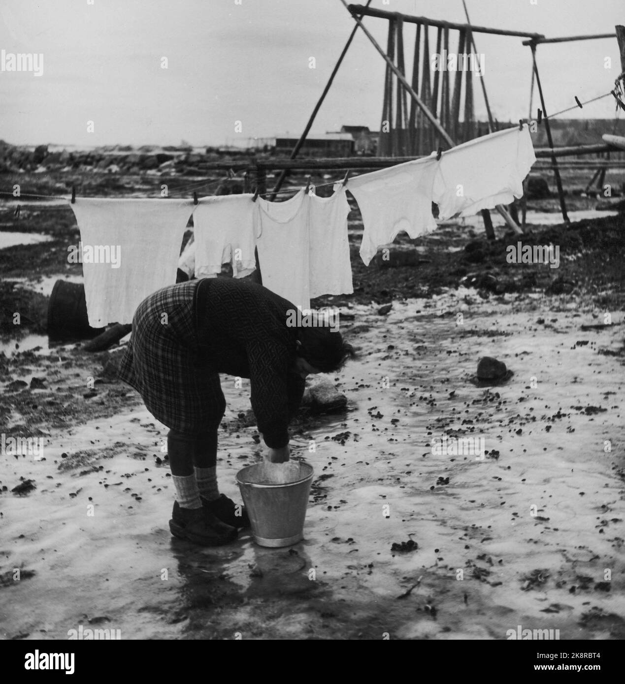 Lofoten in the winter of 1951. Several fishing villages in Lofoten are vacated because they are impossible to operate without electricity, road, quay and telephone connection. In some places, the municipalities have applied for moving money from the state to move the entire population, including the housing houses. Eggum is a place where houses must be moved. Being a housewife at Eggum is a stiff job. Here Sofie Johansen stands and hangs clothes on the hollow outside the house. Photo: Sverre A. Børretzen / Current / NTB Stock Photo