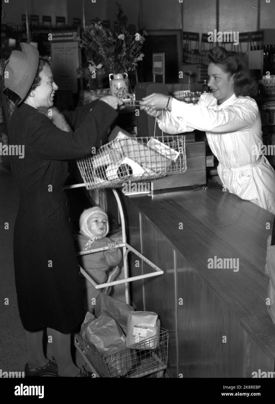 Oslo 1947: Rationing goods lasted long after the war. Here is a young mother who visits Oslo's first self -service shop with her child who has had a trolley to sit on the cart, while the mother can walk along the shelves herself and pick out the goods she needs. The goods are packed, price and brand value are on the package. Here with a shopping cart with food. The Norwegian Cooperative National Association 'Snarkjøp' / Samvirkelag in Parkveien 65. Photo: Th. Scotaam / Current / NTB Stock Photo