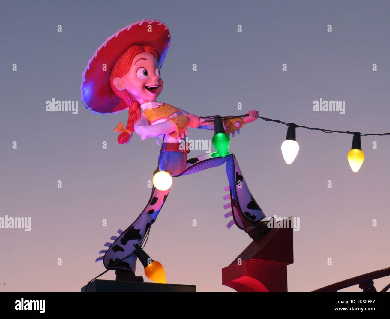 A statue of Jesse from the movie 'Toy Story' holding lights at dusk in Orlando Disney World, Florida Stock Photo