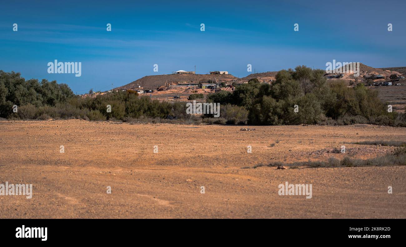 A view of deserted land with buildings in the distance, Coober Pedy