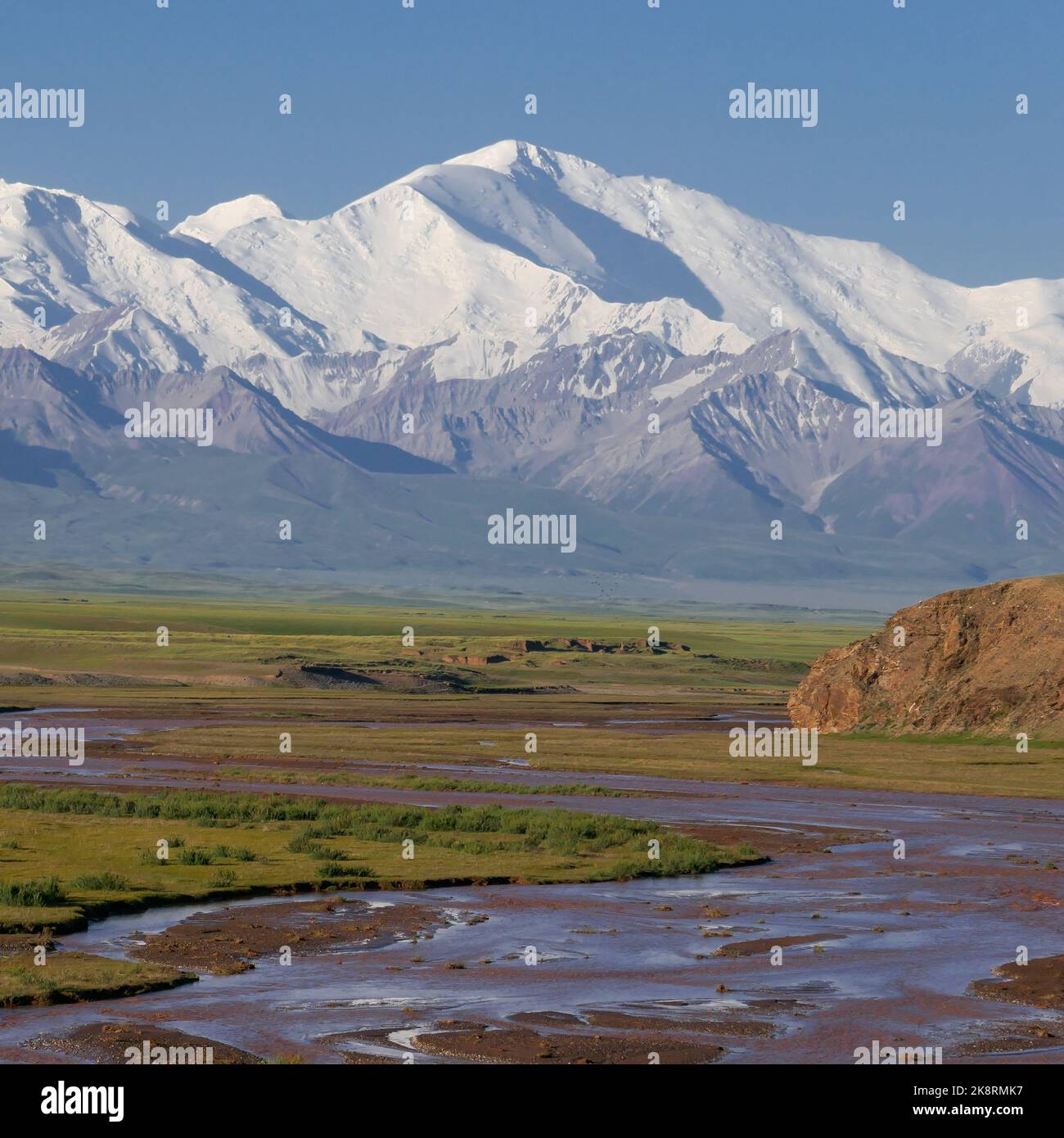 Colorful view of Lenin Peak aka Ibn Sina Peak in the snow-capped Trans Alay mountain range in southern Kyrgyzstan with Kyzyl Suu river in foreground Stock Photo