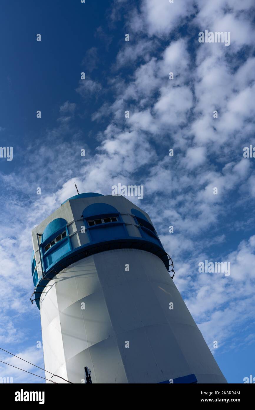 A vertical low-angle closeup of a lighthouse with cloudy sky background ...
