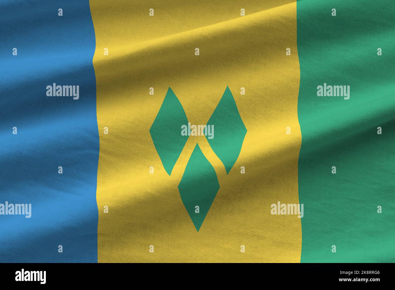 Saint Vincent and the Grenadines flag with big folds waving close up under the studio light indoors. The official symbols and colors in fabric banner Stock Photo