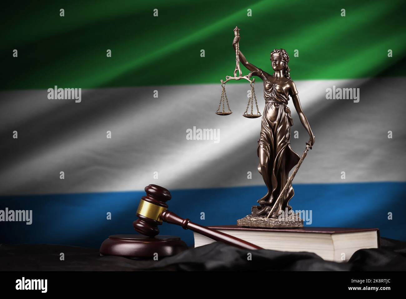 Sierra Leone flag with statue of lady justice, constitution and judge hammer on black drapery. Concept of judgement and punishment Stock Photo