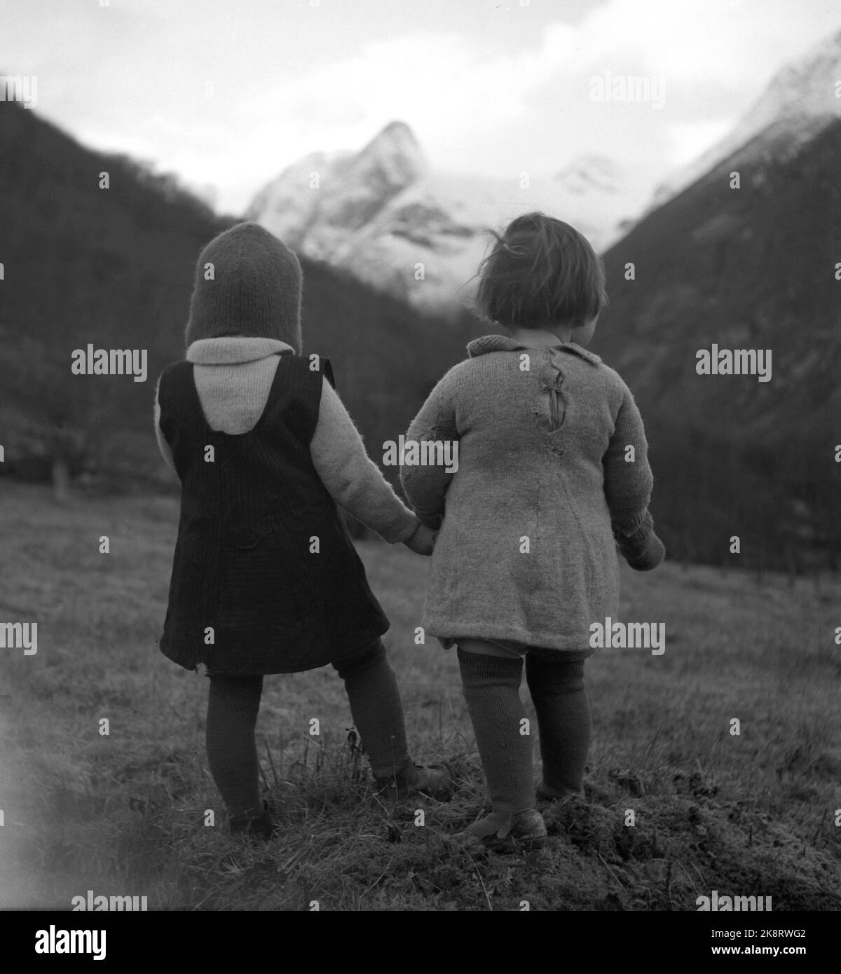 Loen 1947 Two little girls look up at the threatening mountains around Loen, who have twice experienced major RAS disasters. The girls are the sisters Marit and Jorunn Sande. They are the only kids in the village of Bødal- who before the accident had a small primary school. The girls wear tired dresses, socks and shoes. Photo: Th. Scotaam / Current / NTB Stock Photo