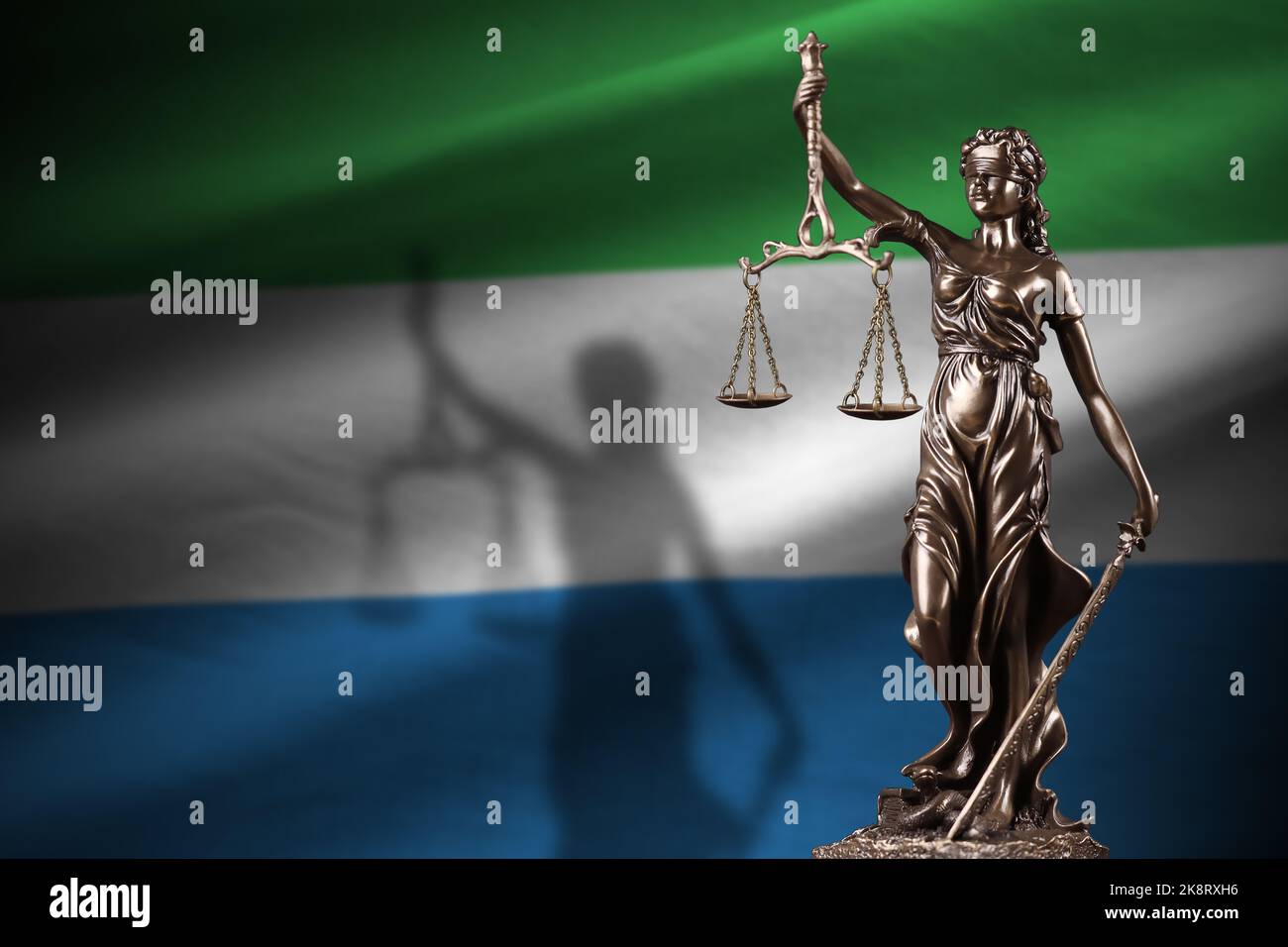 Sierra Leone flag with statue of lady justice and judicial scales in dark room. Concept of judgement and punishment, background for jury topics Stock Photo