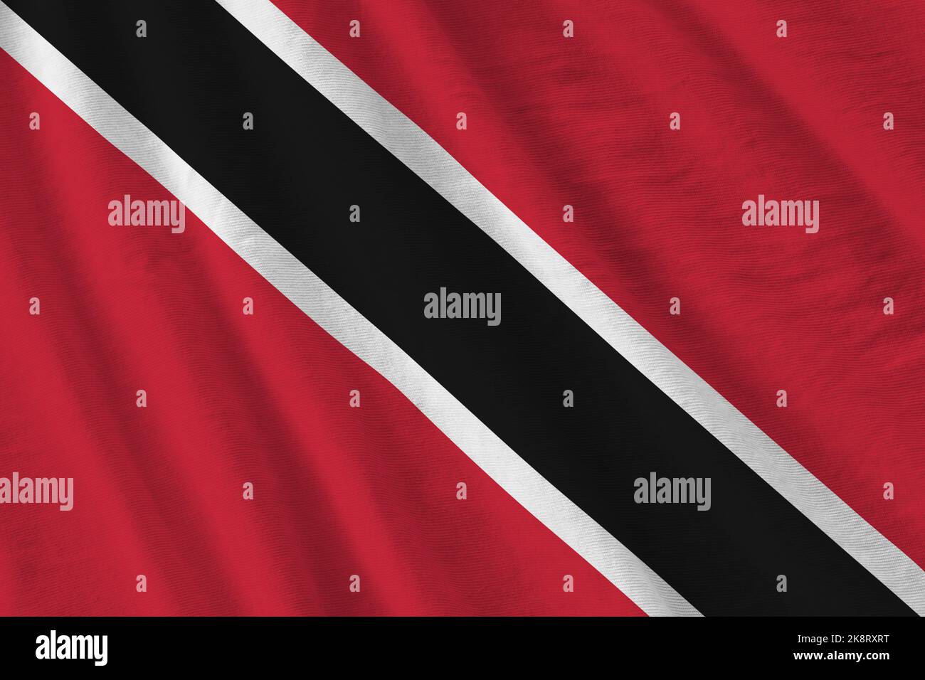 Trinidad and Tobago flag with big folds waving close up under the studio light indoors. The official symbols and colors in fabric banner Stock Photo