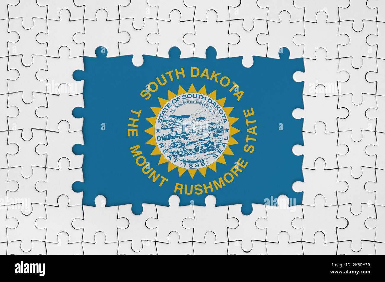 South Dakota US state flag in frame of white puzzle pieces with missing central parts Stock Photo