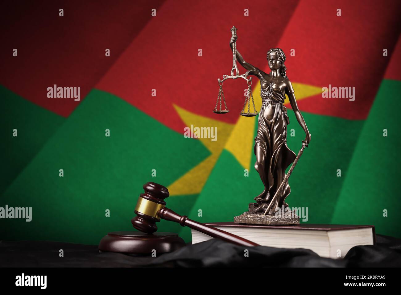 Burkina Faso flag with statue of lady justice, constitution and judge hammer on black drapery. Concept of judgement and punishment Stock Photo