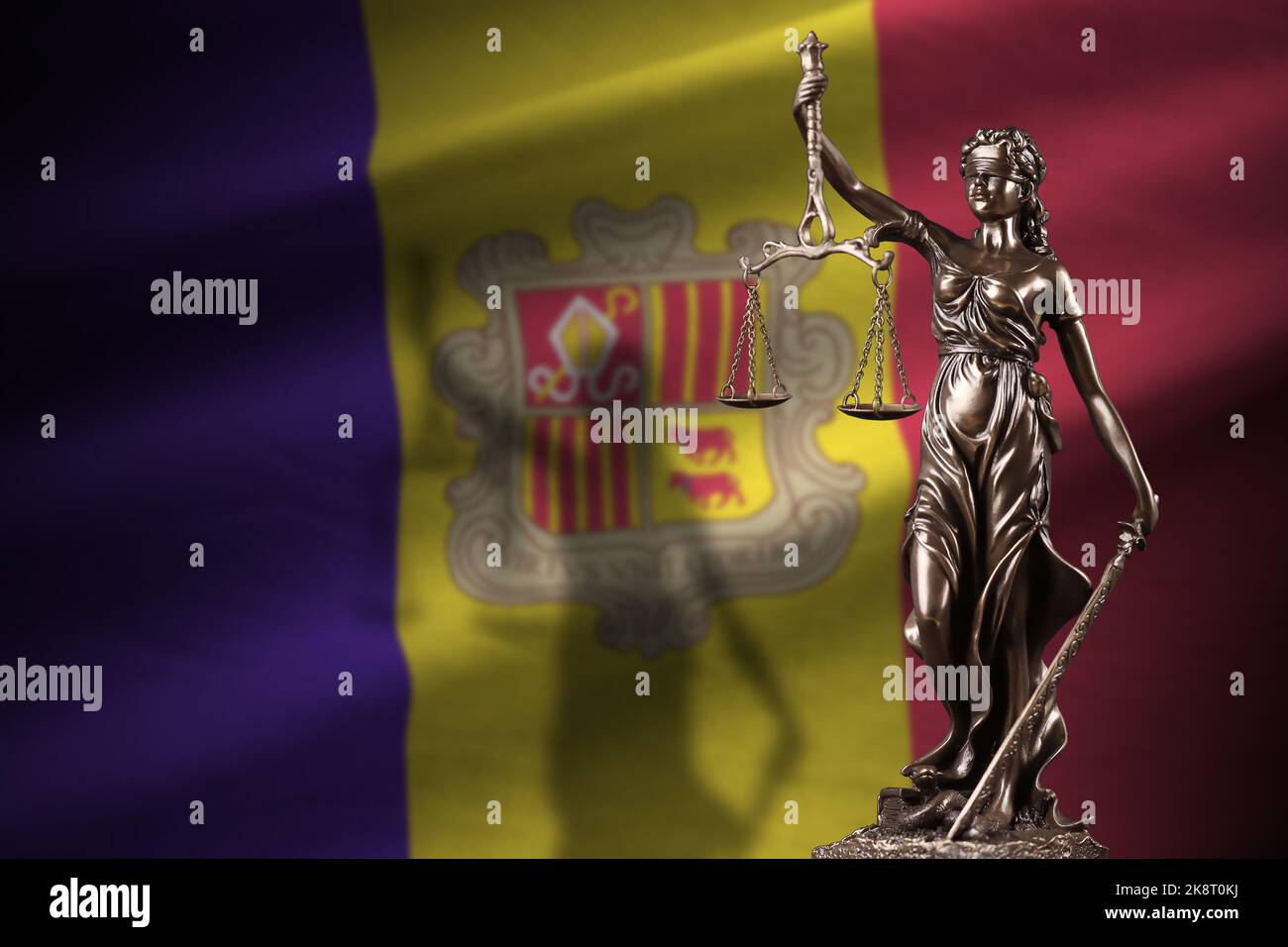 Andorra flag with statue of lady justice and judicial scales in dark room. Concept of judgement and punishment, background for jury topics Stock Photo