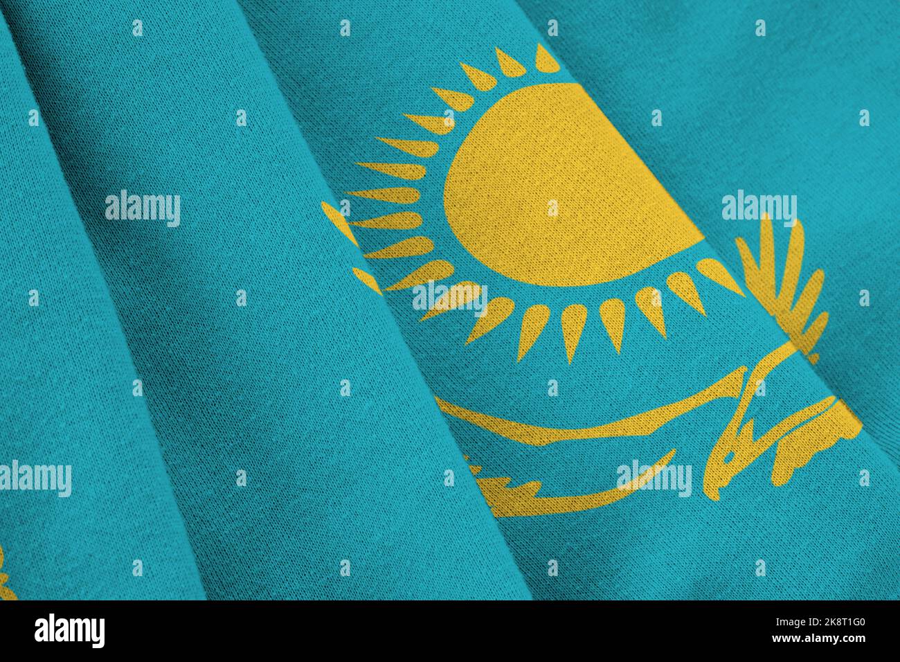 Kazakhstan flag with big folds waving close up under the studio light indoors. The official symbols and colors in fabric banner Stock Photo