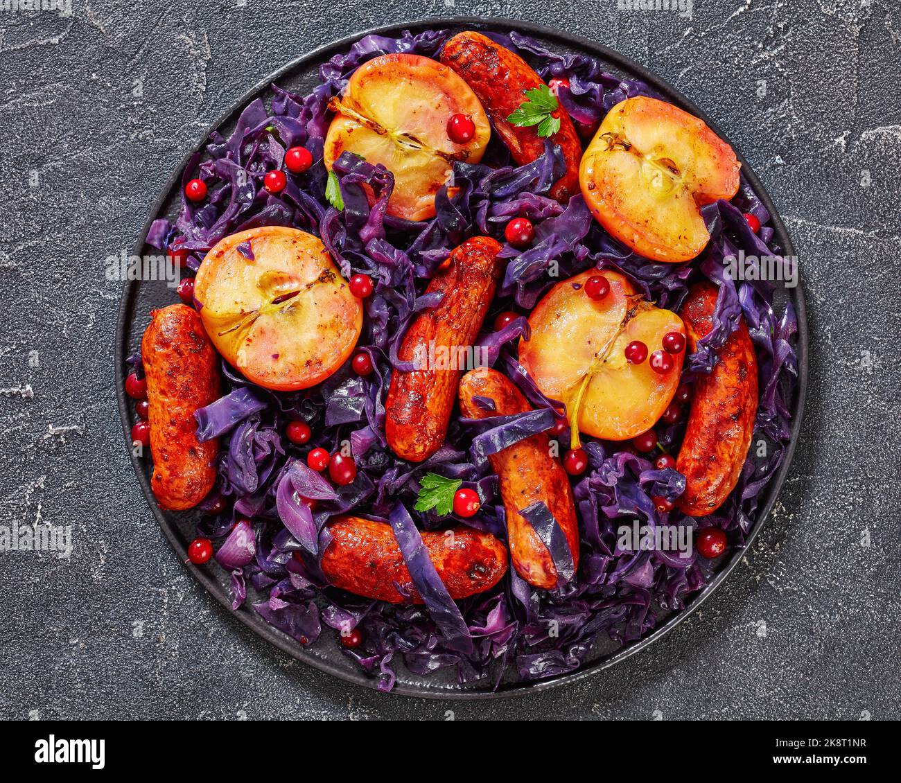 Seared Sausage, Red Cabbage and Apples with cranberries on black plate