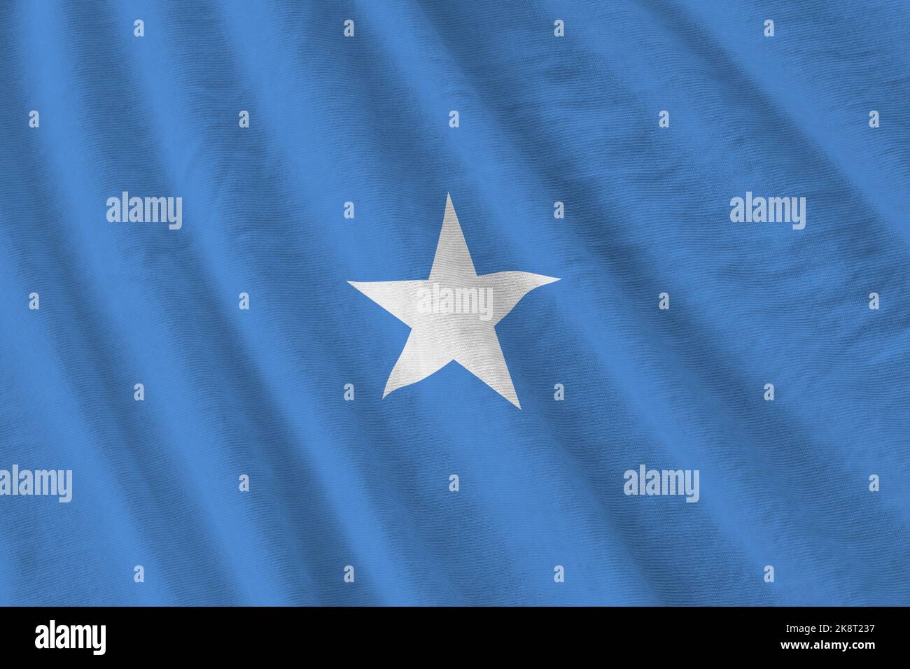 Somalia flag with big folds waving close up under the studio light indoors. The official symbols and colors in fabric banner Stock Photo
