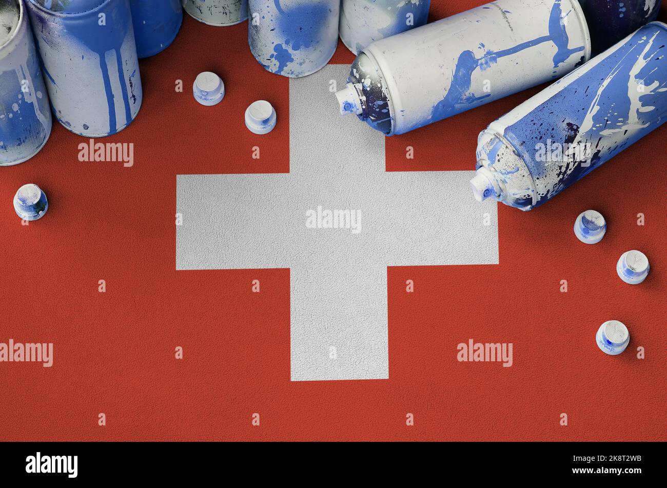 Switzerland flag and few used aerosol spray cans for graffiti painting