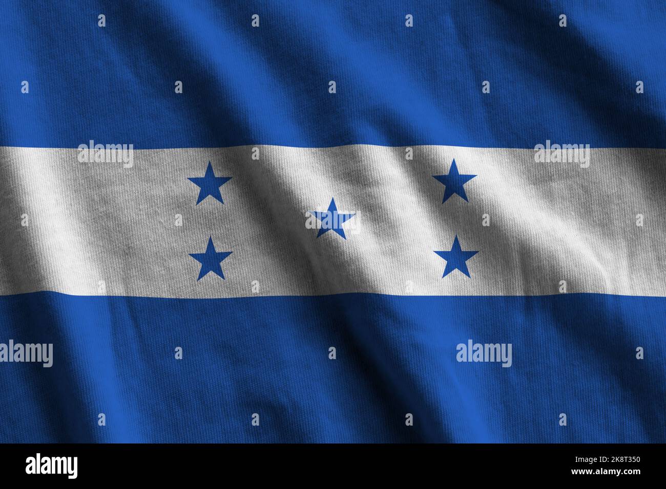 Honduras flag with big folds waving close up under the studio light indoors. The official symbols and colors in fabric banner Stock Photo