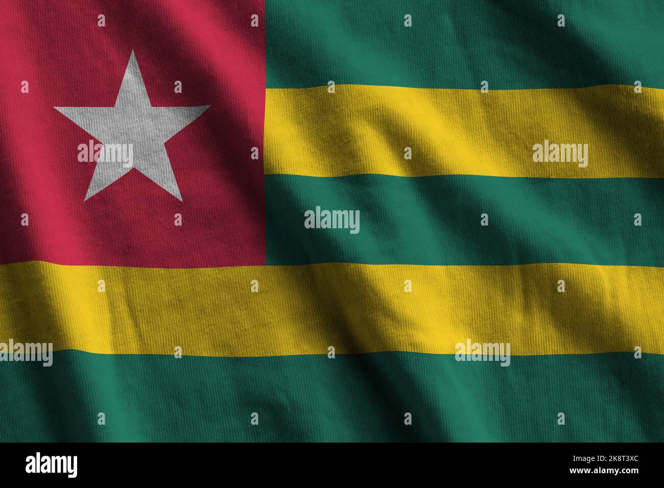 Togo flag with big folds waving close up under the studio light indoors. The official symbols and colors in fabric banner Stock Photo
