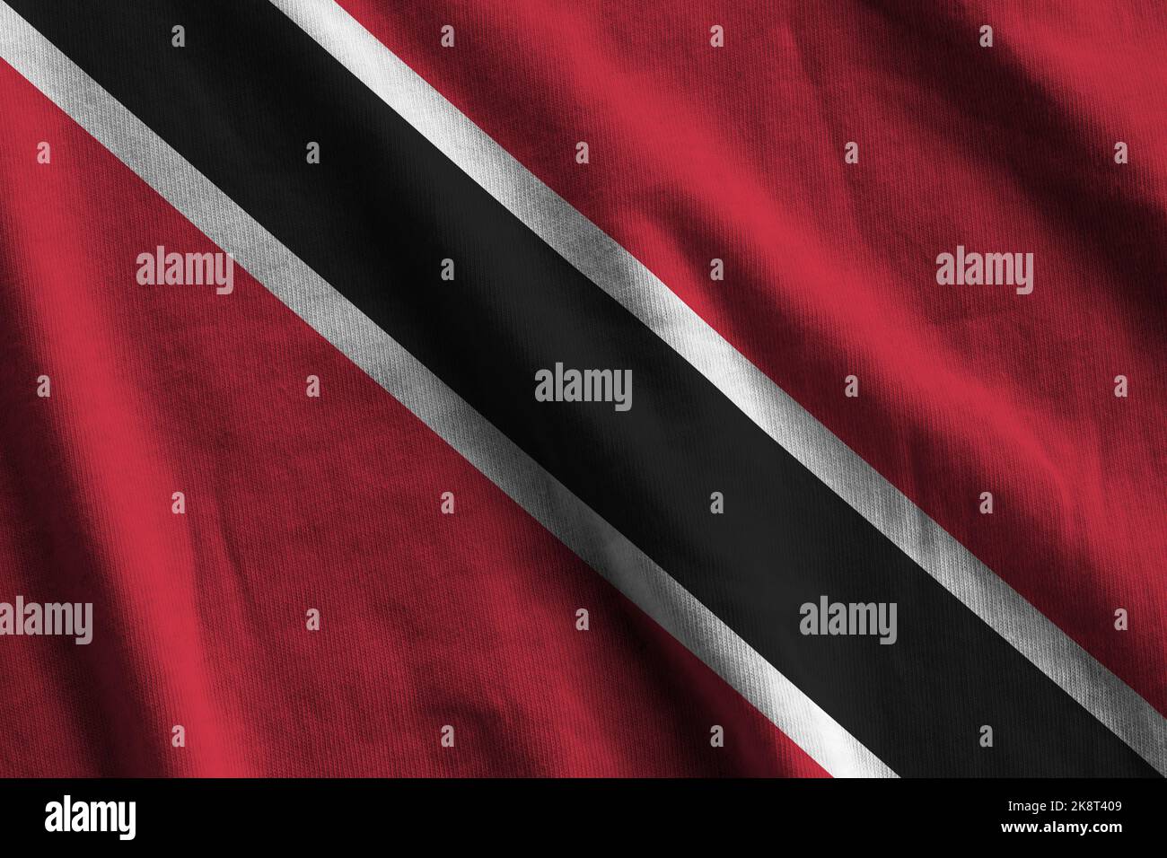 Trinidad and Tobago flag with big folds waving close up under the studio light indoors. The official symbols and colors in fabric banner Stock Photo