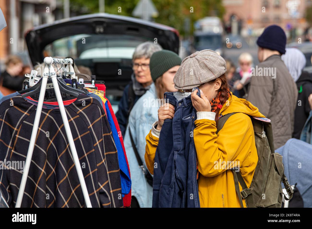 Woman smelling out secondhand jeans at Moron peräkonttikirppis car boot sale in Keskustori, Tampere, Finland Stock Photo