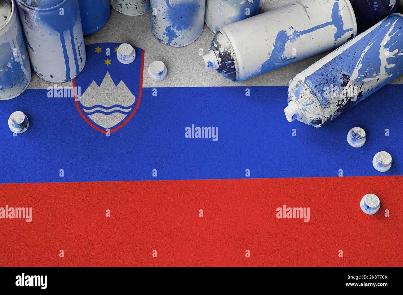 Slovenia flag and few used aerosol spray cans for graffiti painting. Street art culture concept, vandalism problems Stock Photo