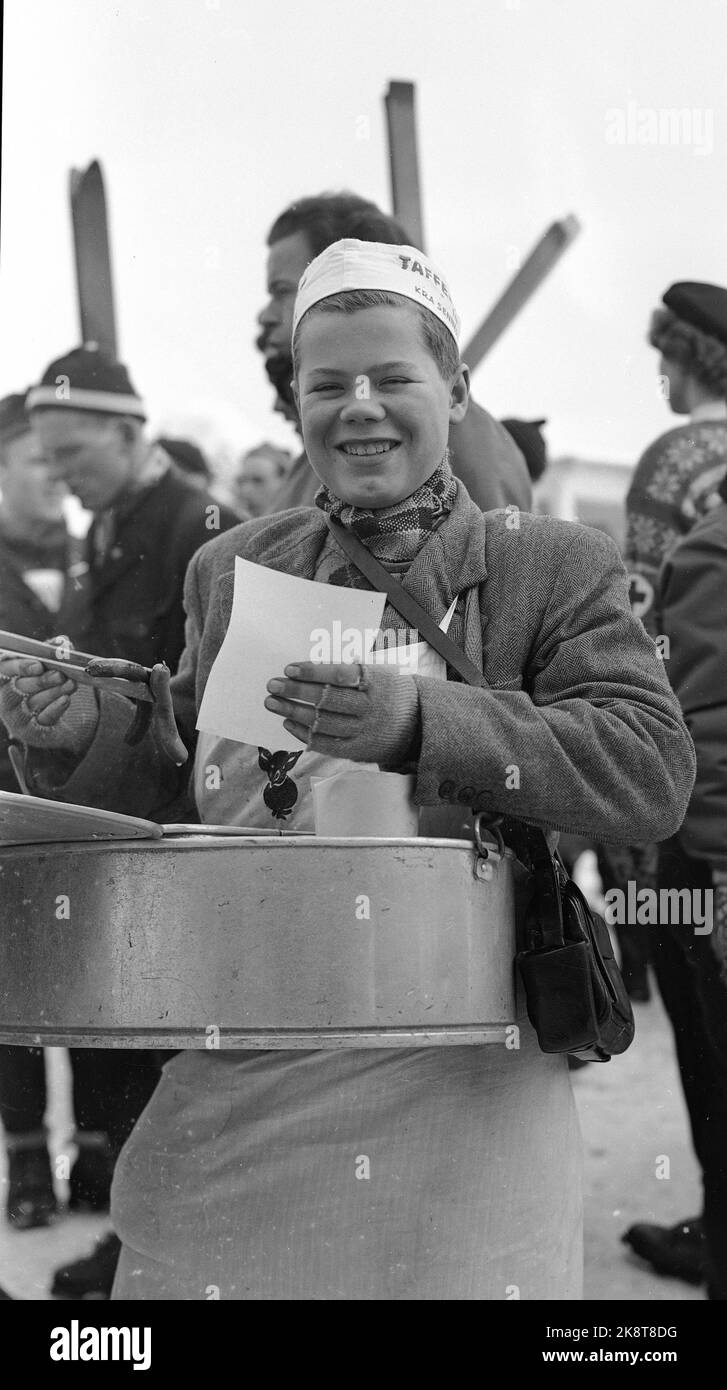 Oslo March 1951 Holmenkollagen. A young sausage seller,- properly dressed with apron, half-swanks, hood on the hair and big smile sells hot sausages in paper during the jumping race on Holmenkollagen. One can guess that his father is a tram conductor, since the money bag is equipped with a futteral for a cut ... Photo: Current / NTB Stock Photo