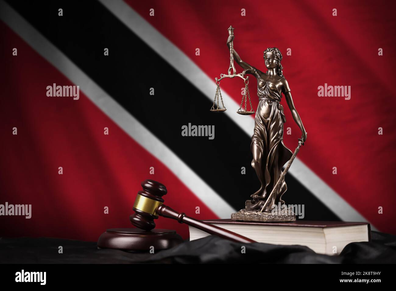 Trinidad and Tobago flag with statue of lady justice, constitution and judge hammer on black drapery. Concept of judgement and punishment Stock Photo
