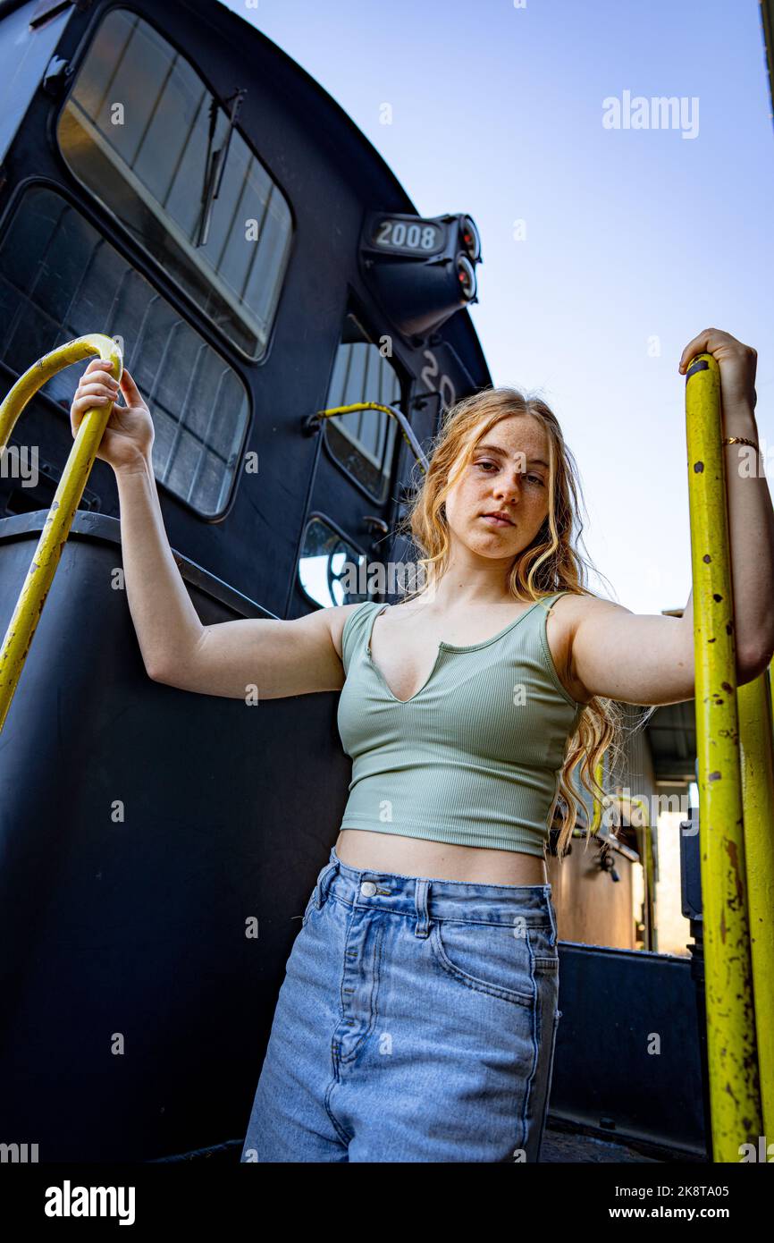 Young Woman Standing on the Stairs of a Diesel Electric Train Engine Stock Photo