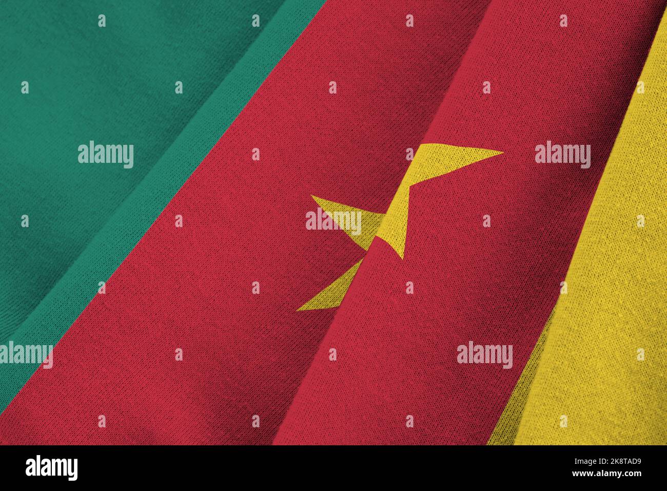 Cameroon flag with big folds waving close up under the studio light indoors. The official symbols and colors in fabric banner Stock Photo