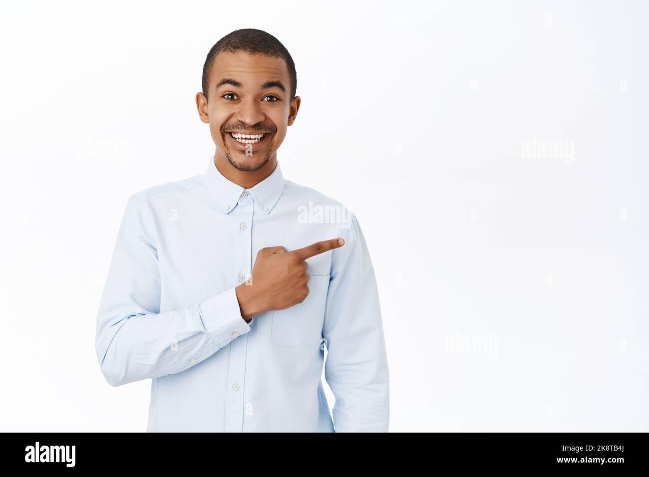 Smiling handsome man pointing right, showing direction, demonstarting promo, standing over white background Stock Photo