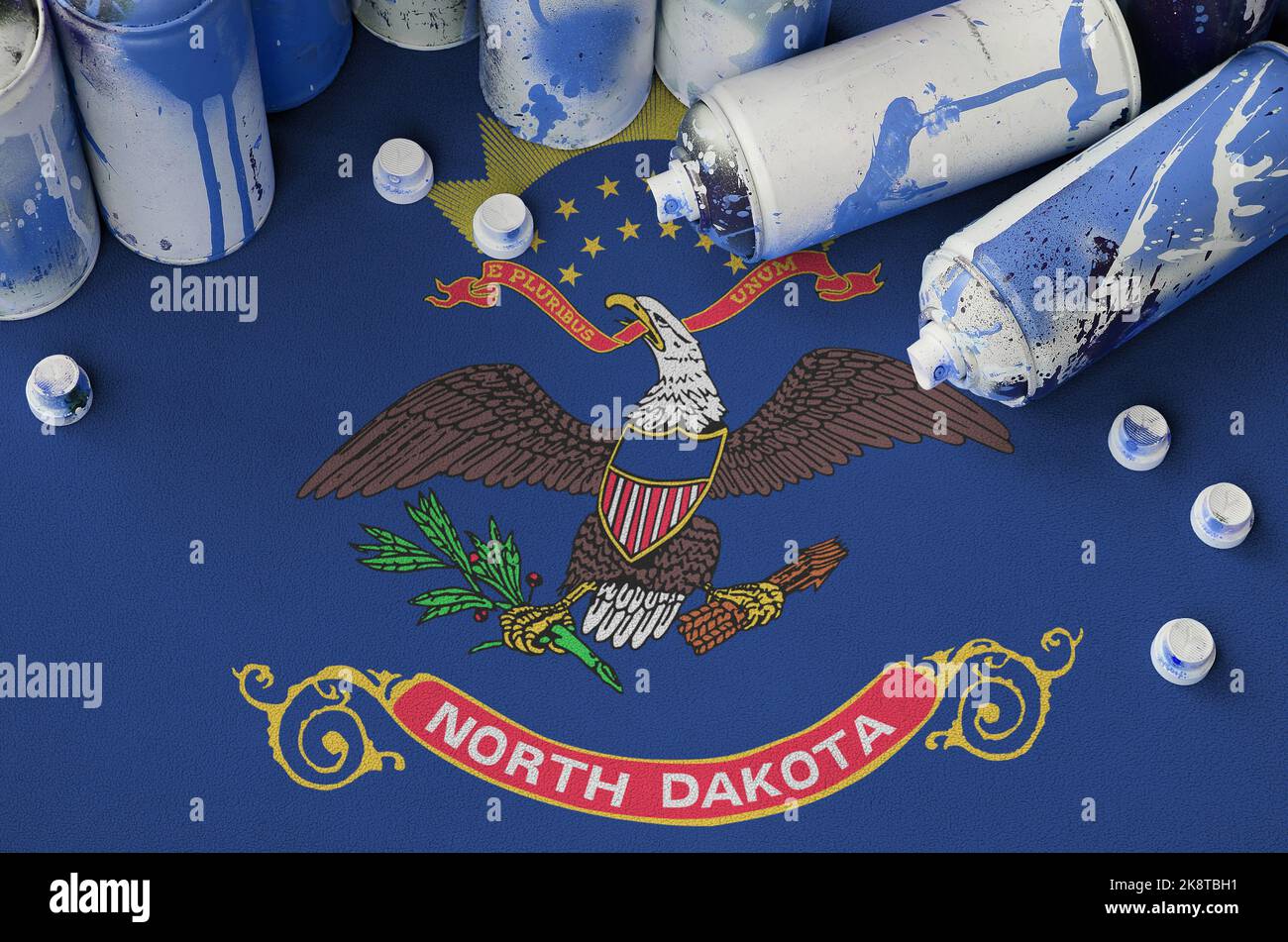 North Dakota US state flag and few used aerosol spray cans for graffiti