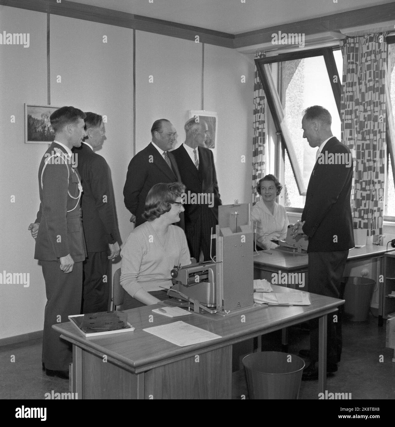 Oslo 19590417. H.M. King Olav V visits the new government building, more specifically the 14th, 15th and 16th floors, ie the Ministry of Justice's offices, the Prime Minister's Office and the representation premises on the 16th floor. Then the government gave a lunch for the king. Here is the king and his follow -up at two office ladies in an office. Prime Minister Einar Gerhardsen (t.h. for the King) and Justice Minister Jens Haugland (until h.). Photo: Jan Stage/NTB Stock Photo