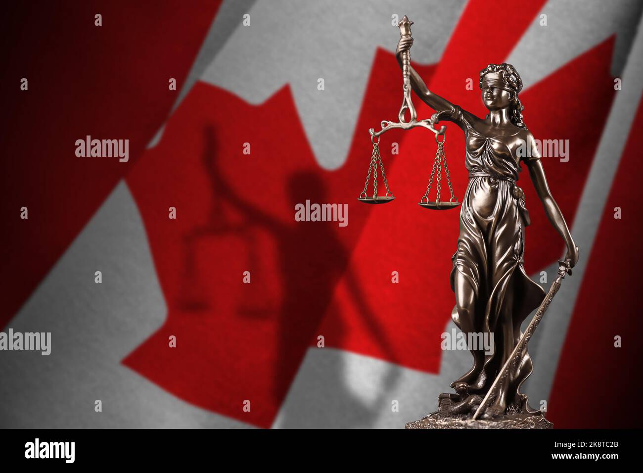 Canada flag with statue of lady justice and judicial scales in dark