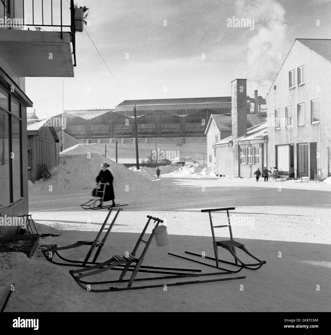 Kirkenes 19620228 Daily life in Kirkenes. Three kicks parked outside the store. Woman on her way to store with kicks. The company Sør-Varanger in the background. Photo: Erik Thorberg / NTB / NTB Stock Photo