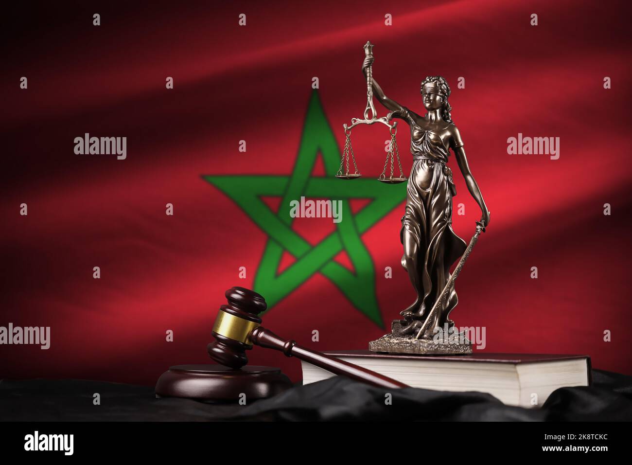 Morocco flag with statue of lady justice, constitution and judge hammer on black drapery. Concept of judgement and punishment Stock Photo
