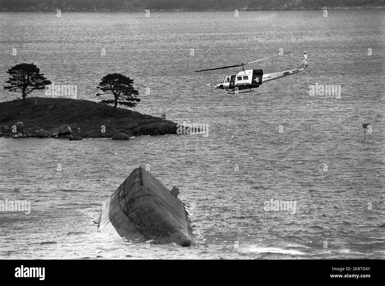 Stavanger 19851105: The cement vessel Concem crashed during the work on Gullfaks B Platform in the Gandsfjord, and 10 people perished. Here the overturned cement bargain. Helicopter is looking for the missing / dead. Photo: Jens O. Kvale / NTB / NTB Stock Photo