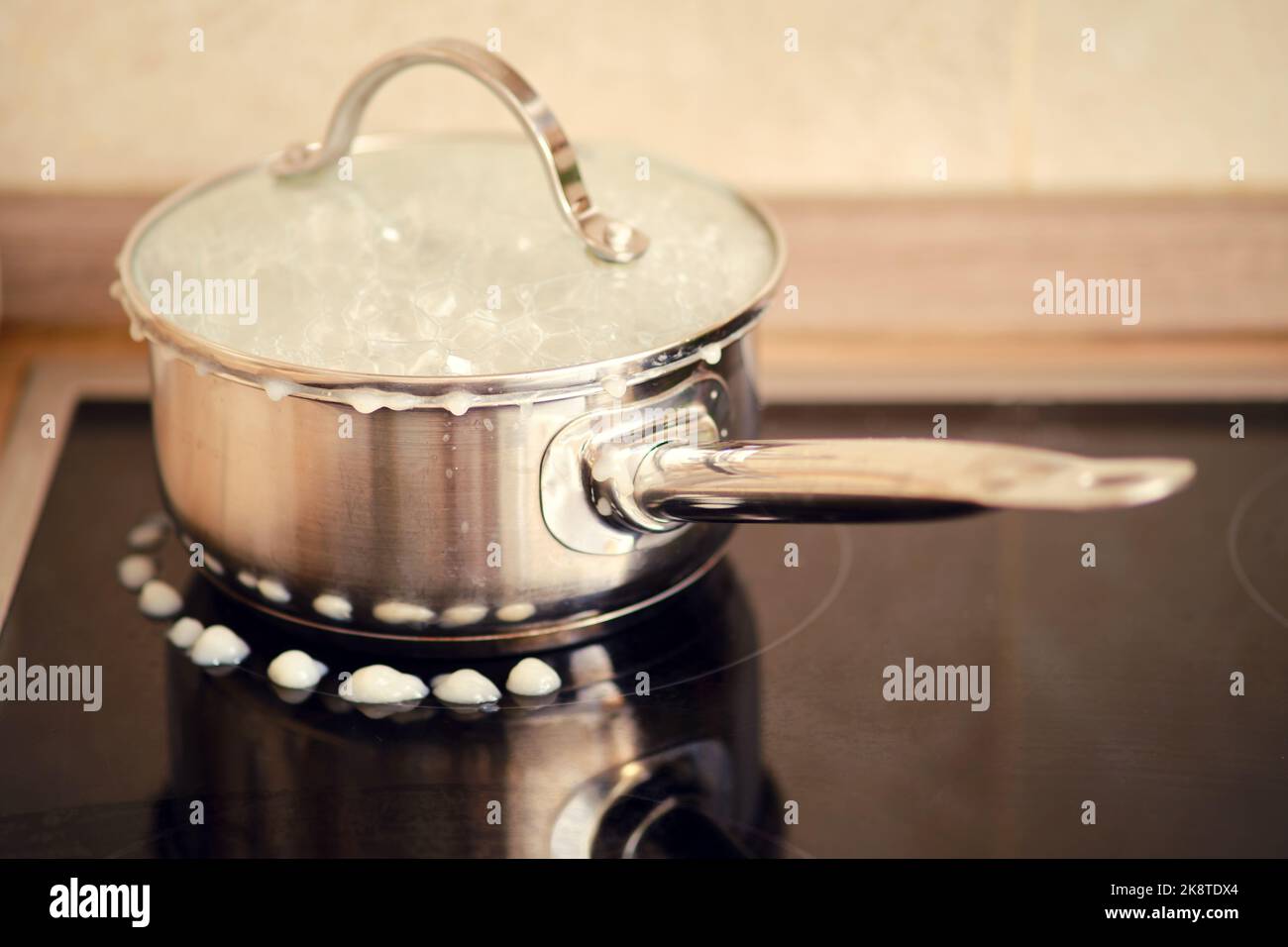 Milk porridge poured out during boiling from under the lid of the pan