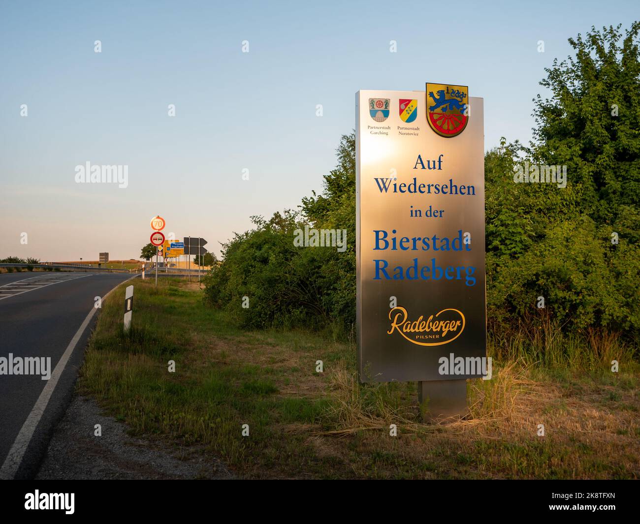 Town exit sign of the beer-loving Radeberg. Leaving the city on the main road and looking on the goodbye board. The rural landscape is in the front. Stock Photo