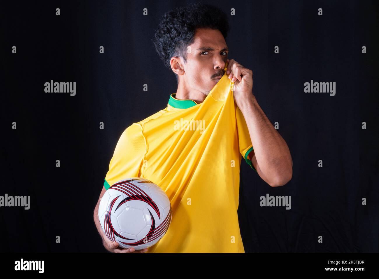 Brazilian Football Black Player Holding Ball and Celebrating, Isolated on Black Background. Stock Photo