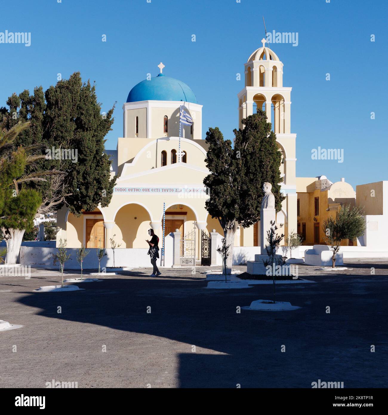 The Church of Saint George aka Perivolas, Oia, Aegean Island of Santorini. Silhouetted male in the courtyard with shadows and trees. Stock Photo