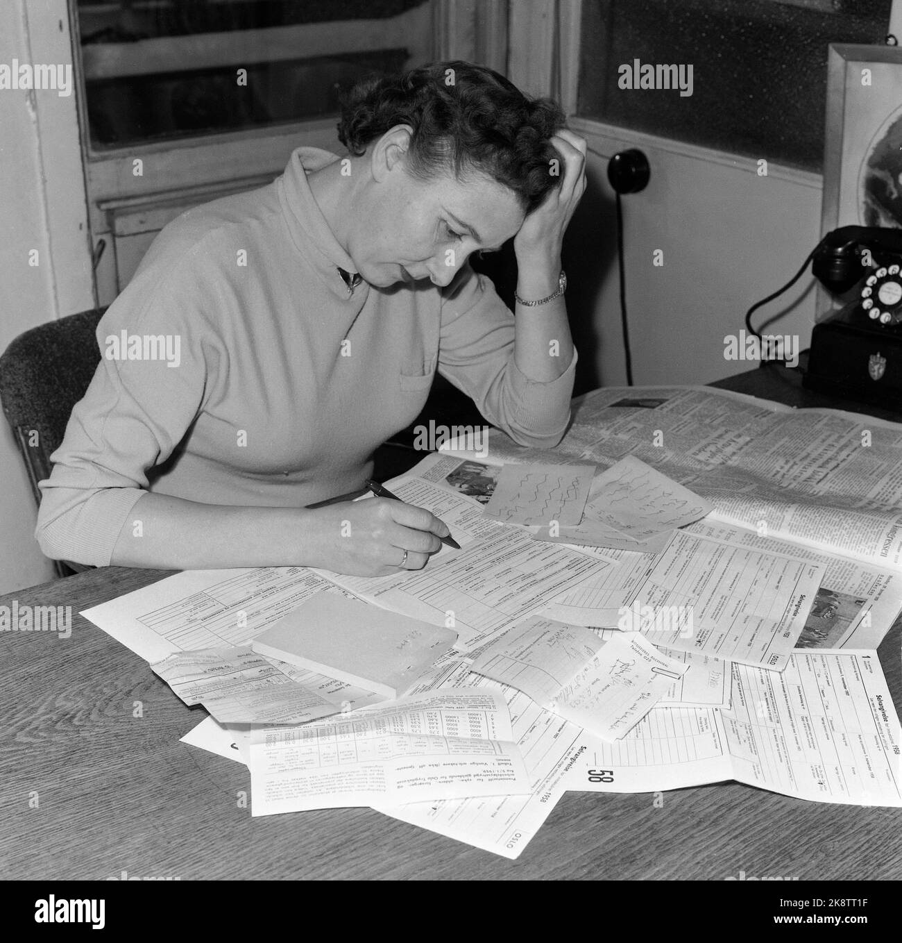 Oslo 19590126 tax return is written. Woman sits with forms and vouchers, thinks and scratches her head. Photo: NTB / NTB Stock Photo