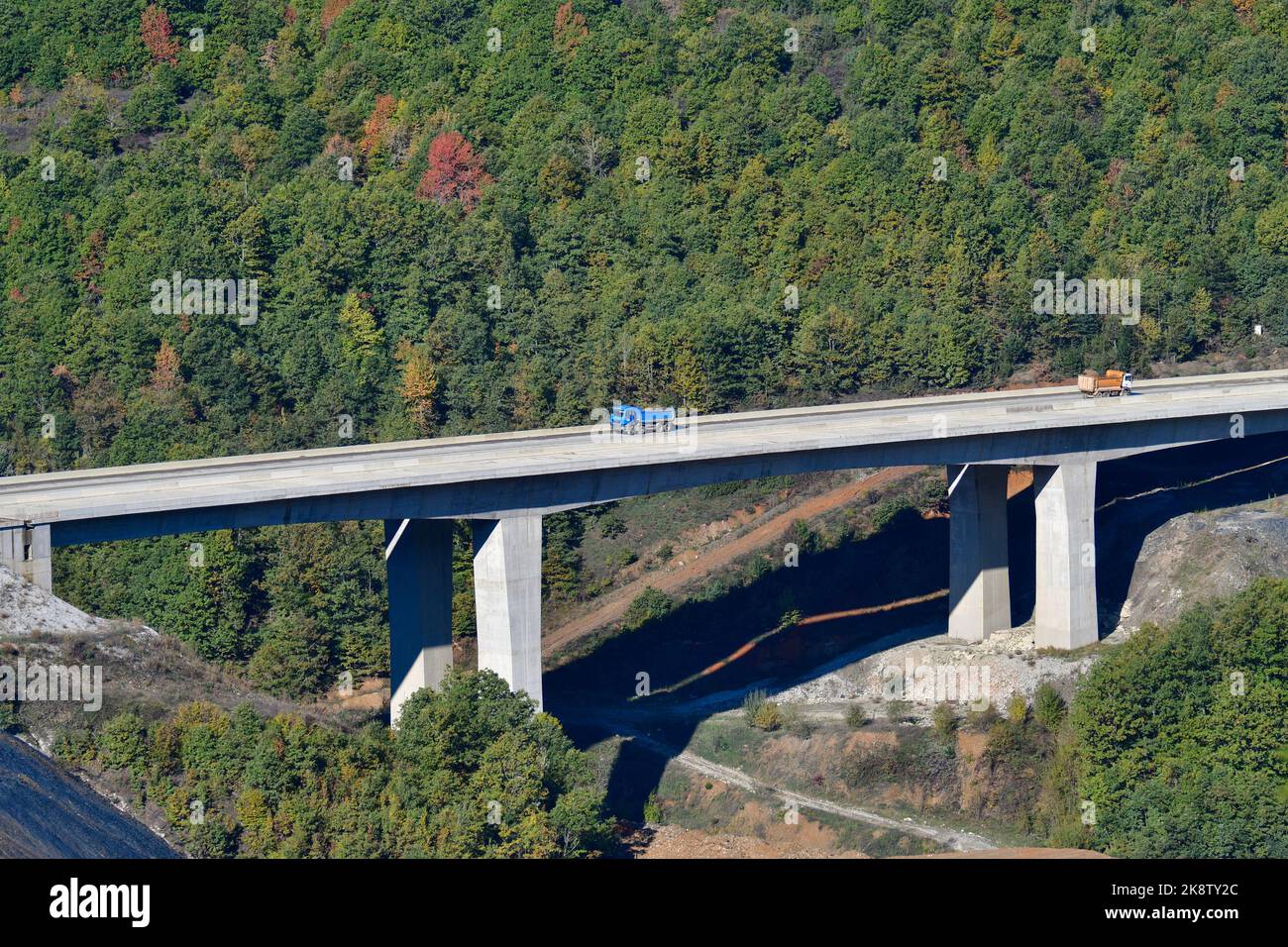 Large trucks transport excavated earth and rocks for highway construction Stock Photo