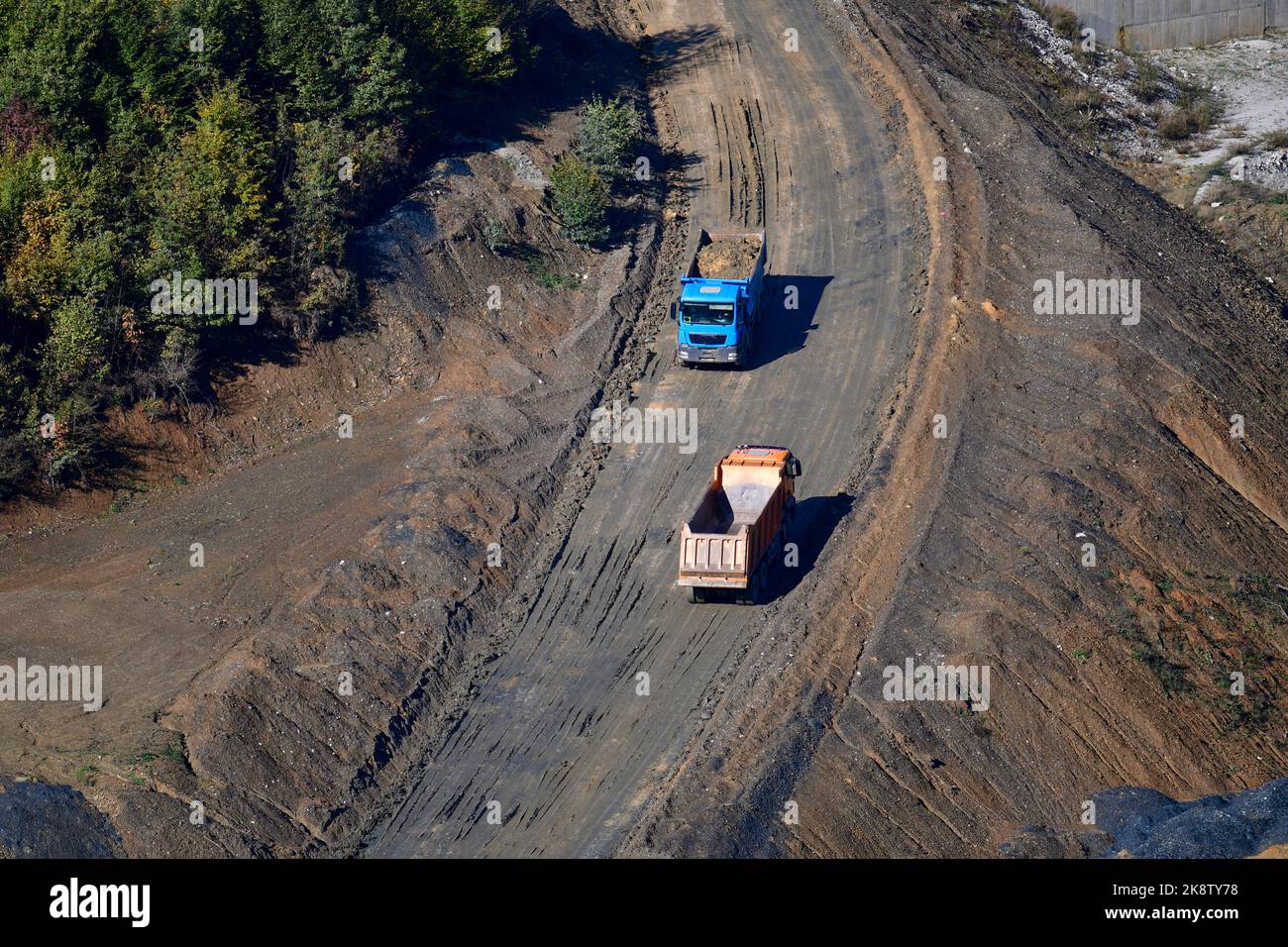 Large trucks transport excavated earth and rocks for highway construction Stock Photo