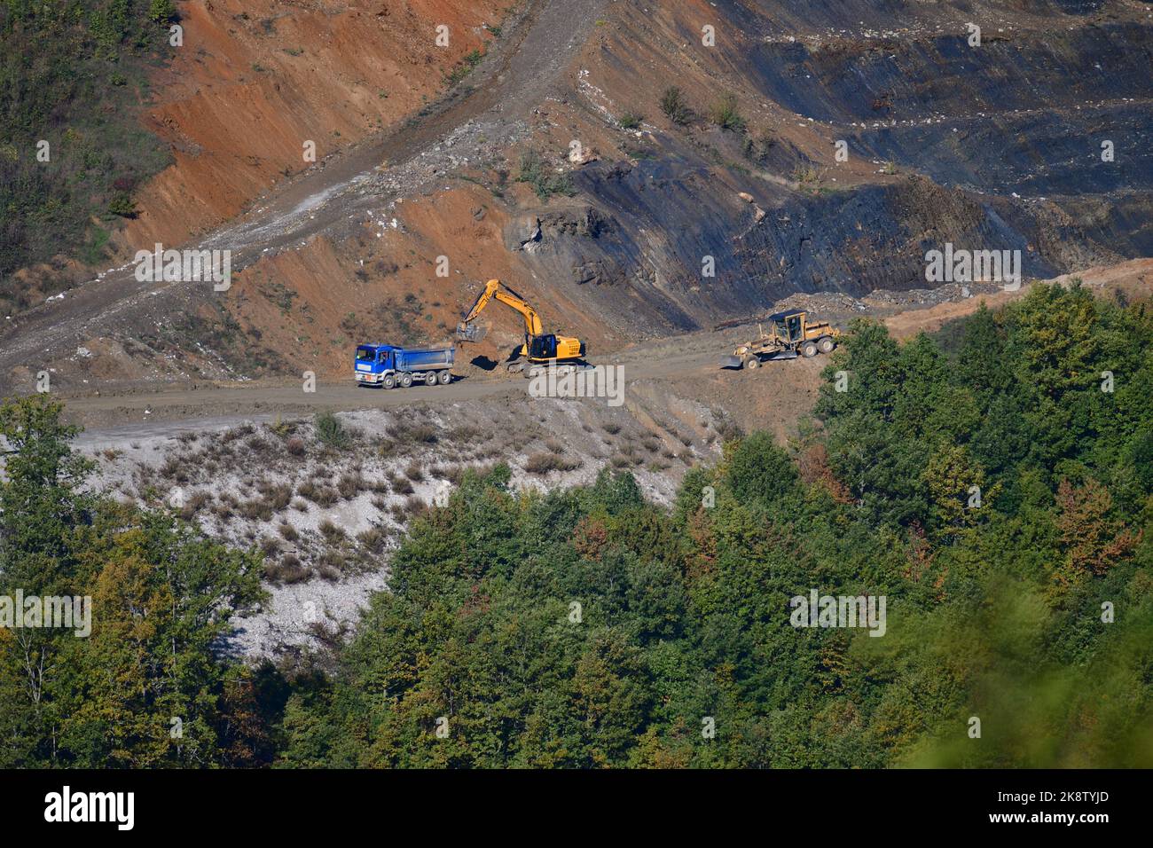 Large trucks transport excavated earth and rocks for highway construction Stock Photo