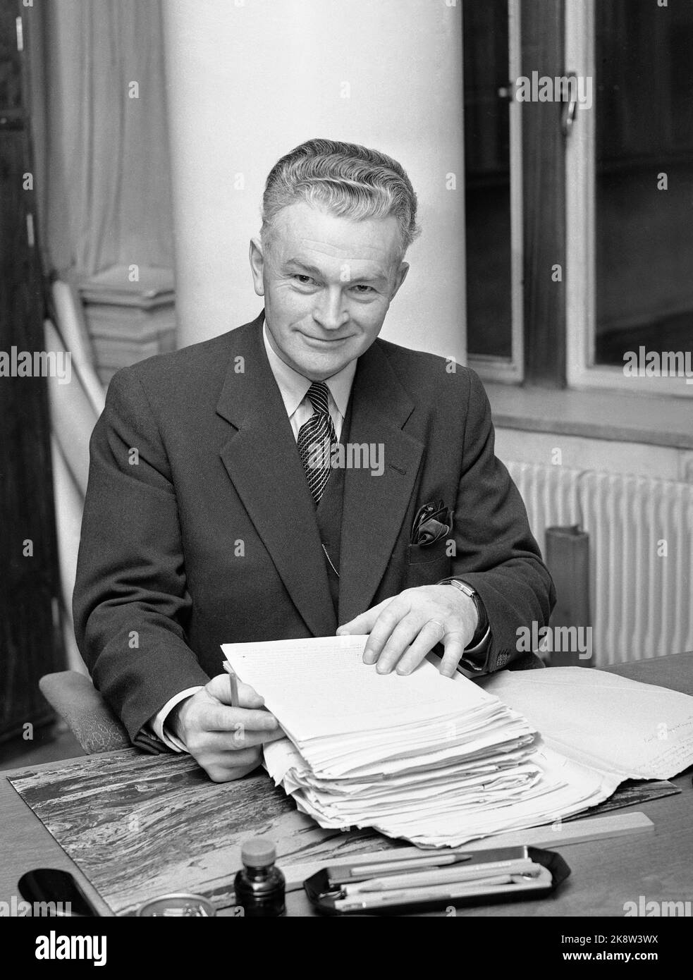 Oslo 19570219 Schei Committee leader Nikolai Schei at the desk with documents. The Schei Committee was reduced to investigate the advantages and disadvantages of merging municipalities in Norway. Their attitude was that the merger was predominantly favorable for small municipalities, with the recommendation facing hard resistance in the relevant municipalities. Nevertheless, the number of municipalities was cut down from well over 700 to around 450 during the 60s. Photo: NTB / NTB Stock Photo
