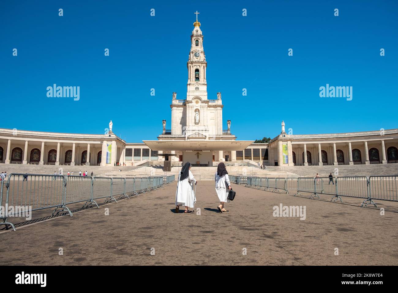 The Sanctuary of Fatima, Portugal. Two nuns passing in front of the Basilica of Our Lady of the Rosary in background. Stock Photo