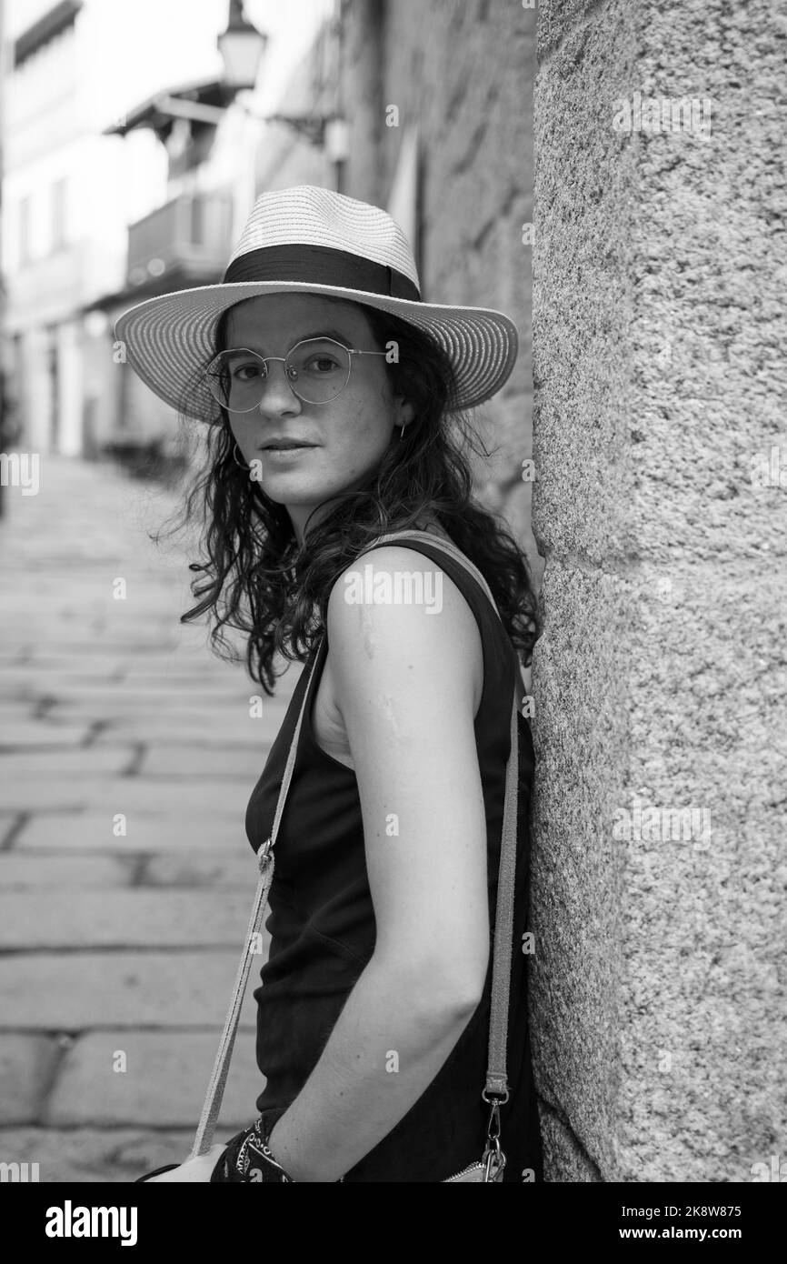 Beautiful young caucasic woman with a hat smiling to the camera in the streets of Spain Stock Photo