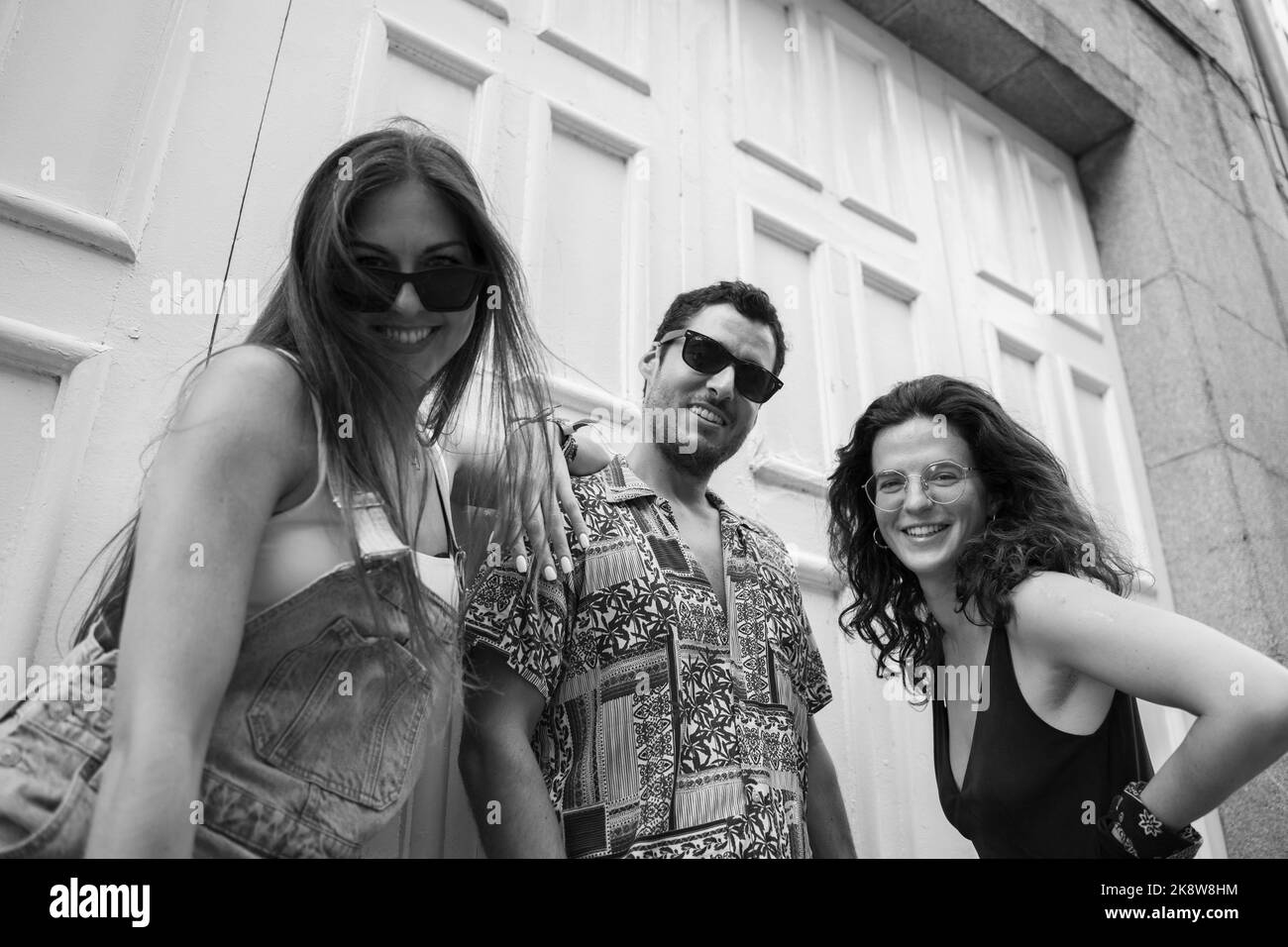 a group of three friends having fun and laughing on a bench in the street Stock Photo