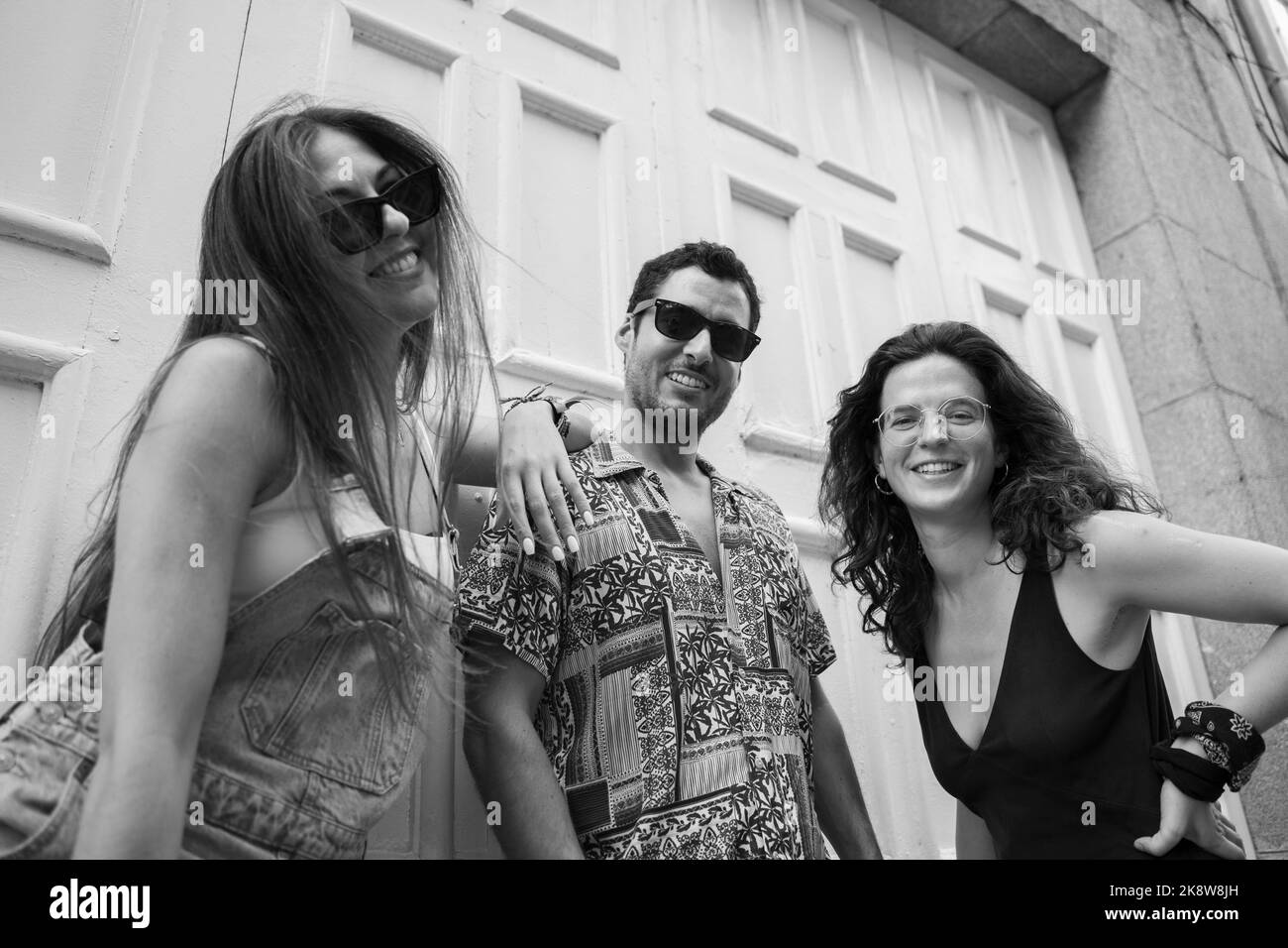 a group of three friends having fun and laughing on a bench in the street Stock Photo